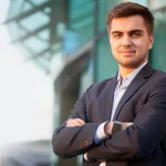 Portrait of a man in a suit against the building with a glass facade